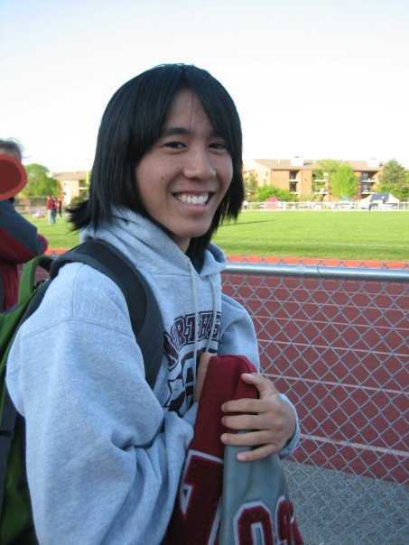 Marina at a track meet, smiling at the camera and clutching a letter jacket.