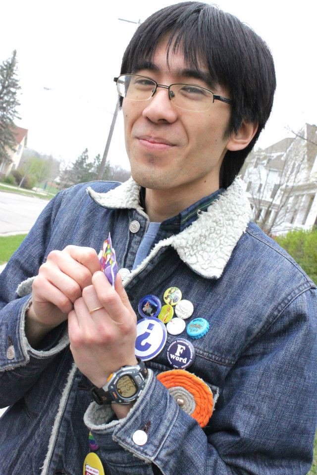 Marina grinning and eating candy, wearing a jean jacket covered with various pins and buttons.