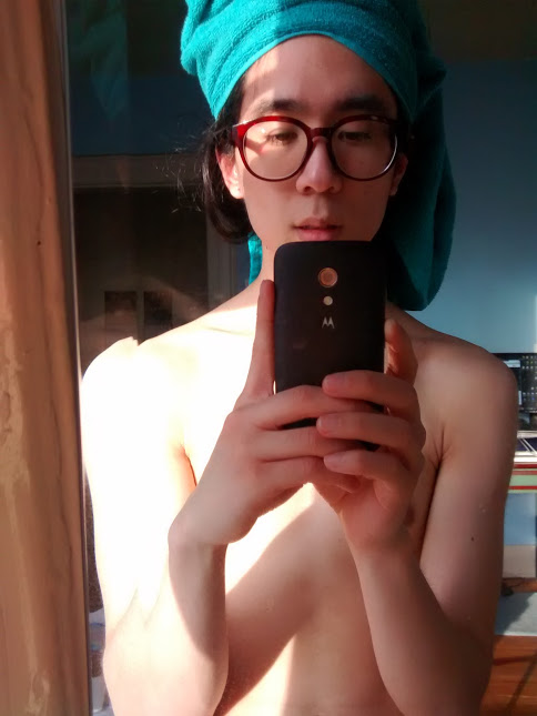 A post shower selfie. Marina has a towel on her head and a patch of bright sunlight falls across part of her body.