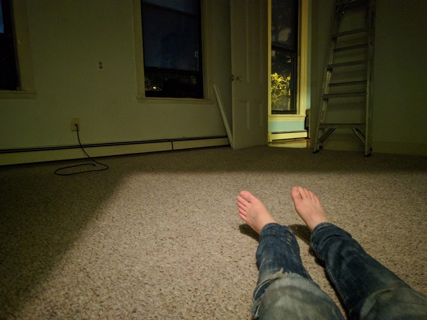 Marina's legs/feet on the ground in her empty apartment.